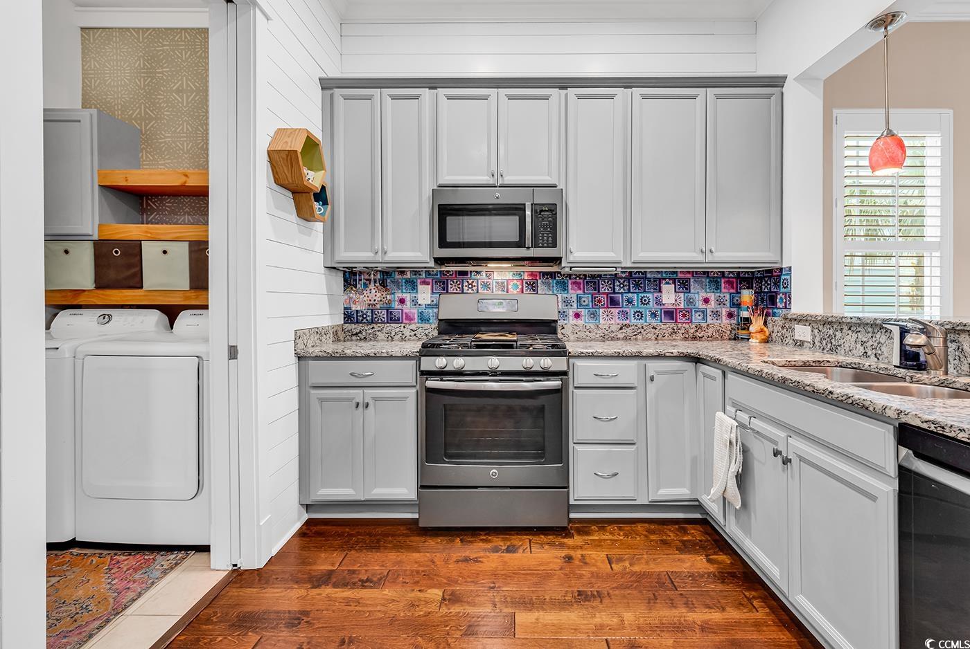 1411 Peterson Street Myrtle Beach, SC 29577 - Photo 8 of 40 Kitchen featuring stainless steel appliances, washing machine and clothes dryer, light stone counters, dark wood-style floors, and decorative backsplash