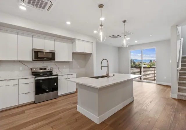 a large kitchen with stainless steel appliances granite countertop a stove a sink dishwasher and a refrigerator with wooden floor