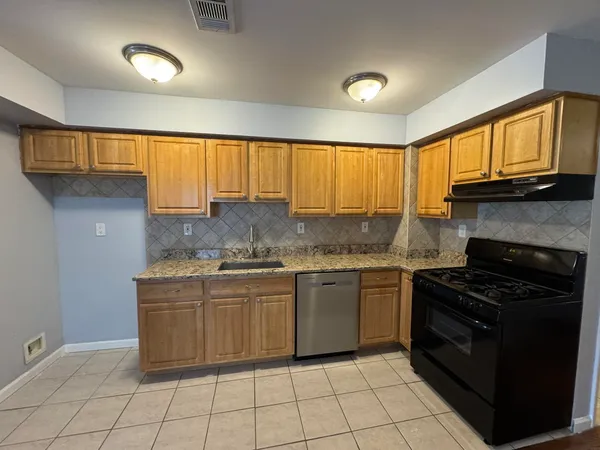 a kitchen with granite countertop a stove sink and cabinets