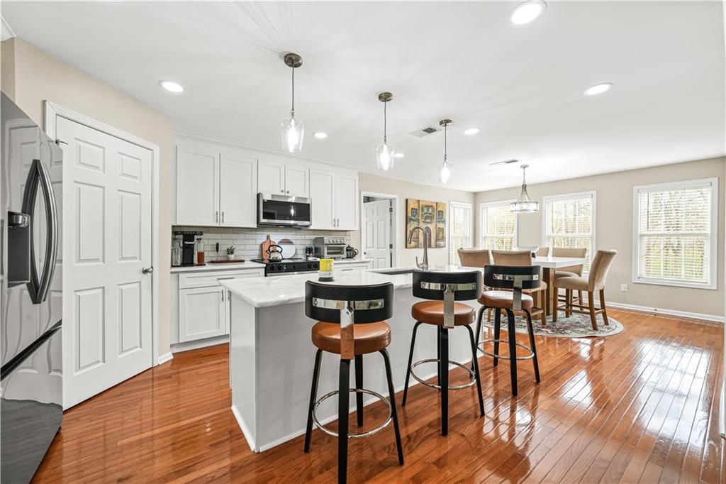 4320 Clarion Drive Conley, GA 30288 - Photo 16 of 49 a kitchen with stainless steel appliances granite countertop a stove top oven a refrigerator a sink and a dining table with wooden floor
