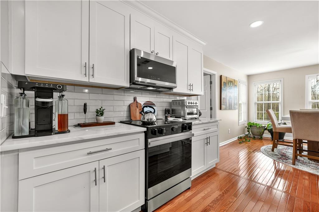 4320 Clarion Drive Conley, GA 30288 - Photo 23 of 49 a kitchen with stainless steel appliances granite countertop a stove top oven a sink dishwasher and white cabinets with wooden floor
