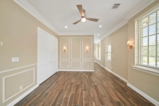 a view of empty room with wooden floor and fan