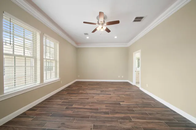 a view of empty room with wooden floor and fan