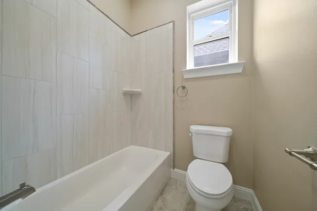 a white toilet sitting next to a white tub
