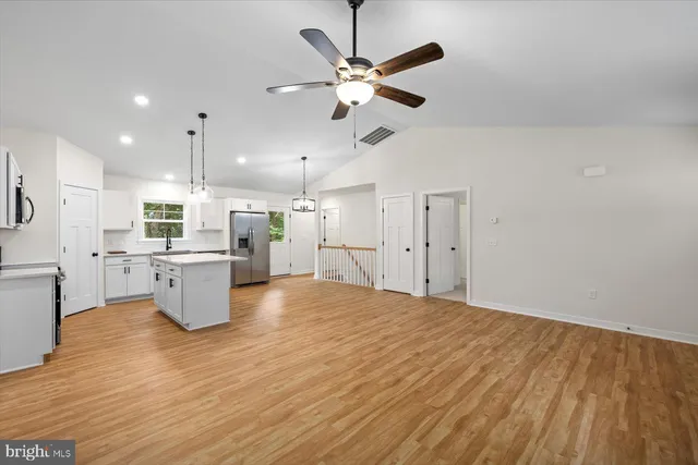 a kitchen with stainless steel appliances a stove a sink and white cabinets with wooden floor