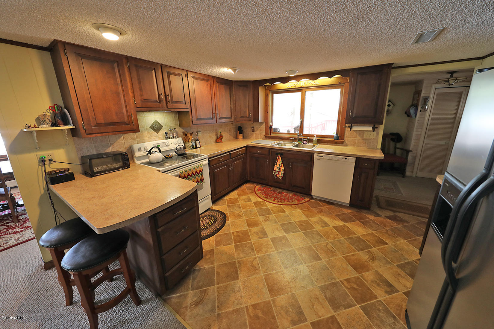 142 Kibbe Road Otis, MA 01029 - Photo 11 of 28 a kitchen with granite countertop a sink a stove a refrigerator with a dining table and chairs