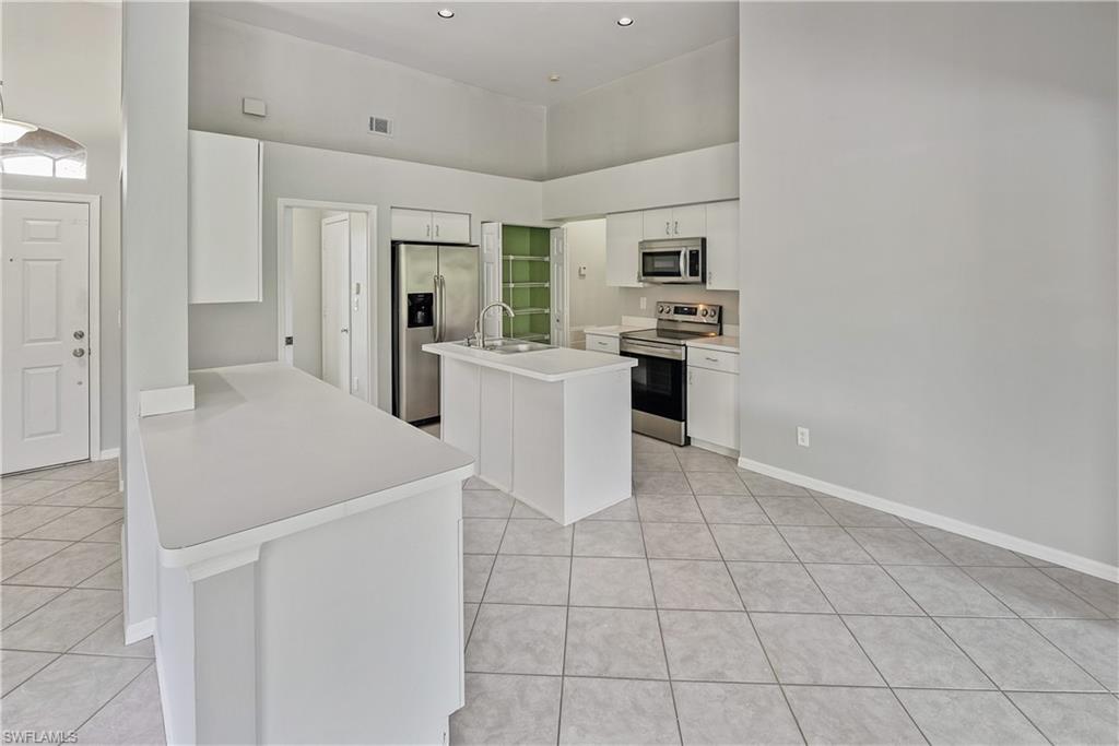 6721 Sloane Place Naples, FL 34104 - Photo 9 of 29 a kitchen with white cabinets and stainless steel appliances