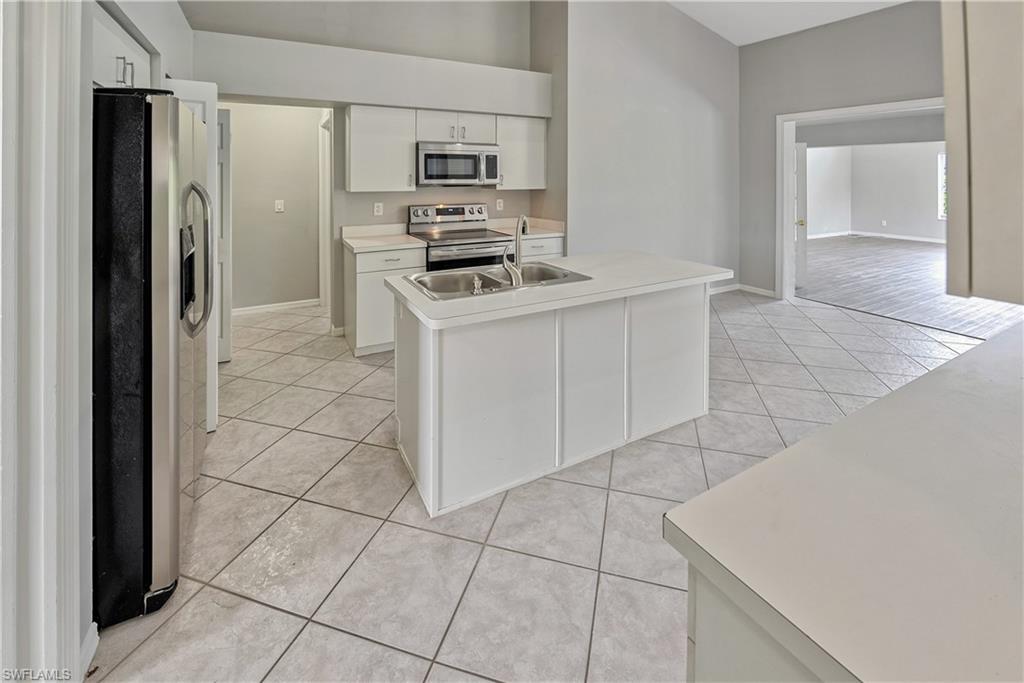 6721 Sloane Place Naples, FL 34104 - Photo 10 of 29 a kitchen with stainless steel appliances a stove a microwave and a refrigerator