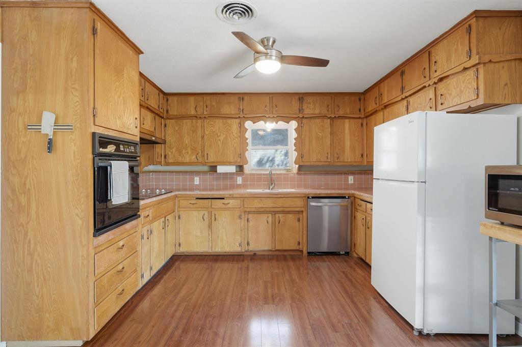 4105 Springbranch Drive Benbrook, TX 76116 - Photo 11 of 27 a kitchen with a sink a refrigerator a washer and dryer with wooden floor