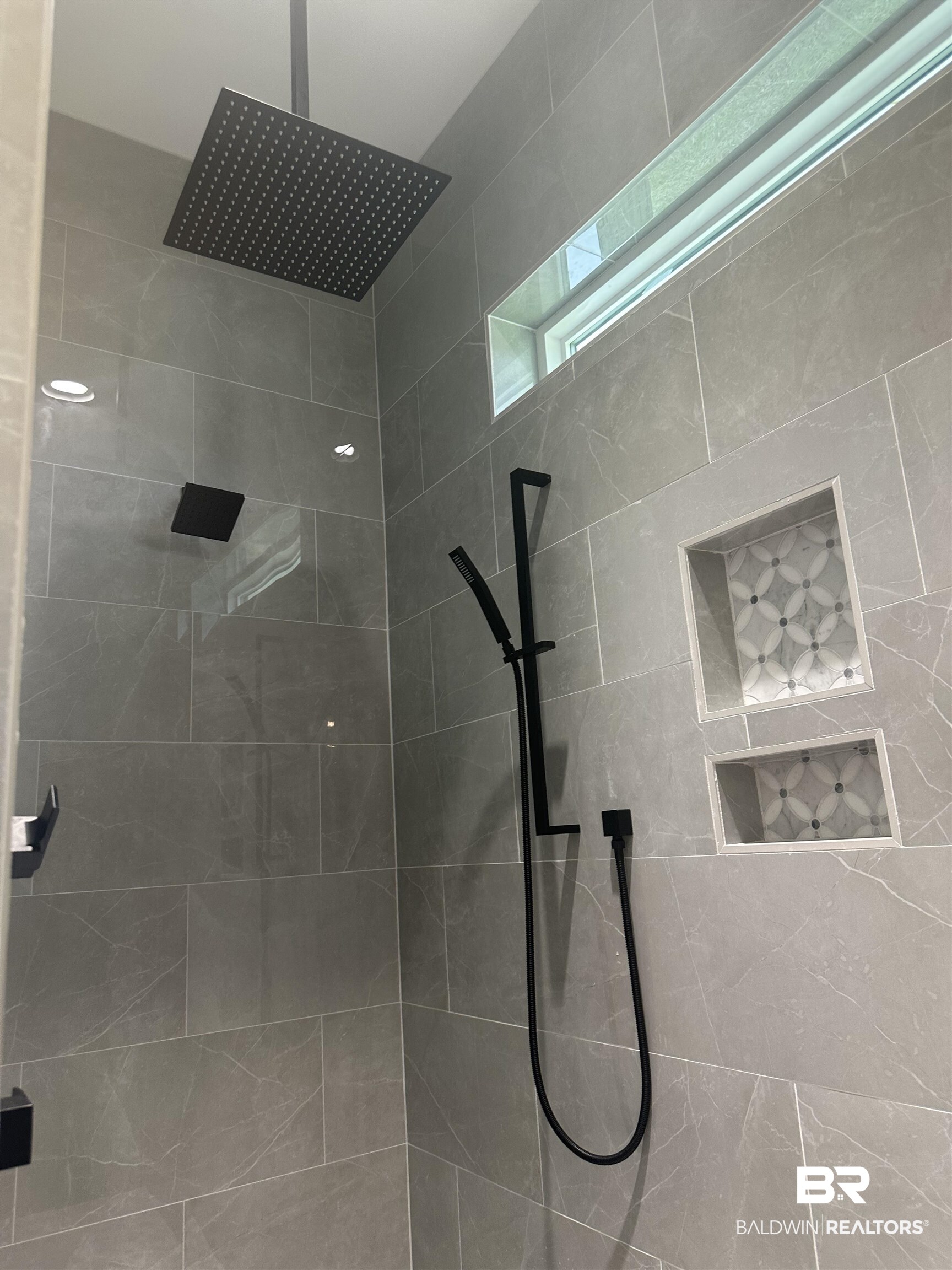13111 Gopher Court Elberta, AL 36530 - Photo 18 of 41 Shower featuring large format gray tile, a rain shower head, matte black fixtures, built-in tiled niches, and a transom window