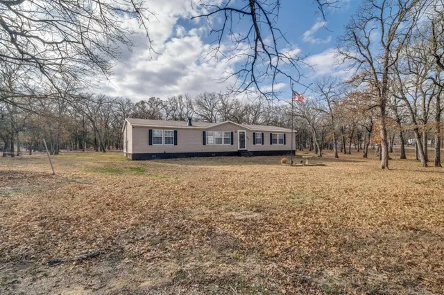a view of house with yard and trees in the background