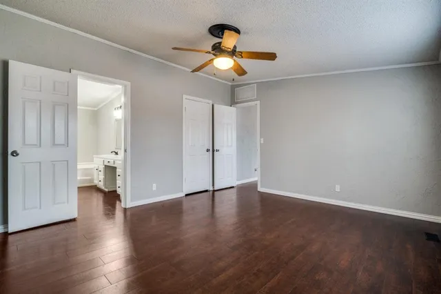 a view of an empty room with wooden floor and a ceiling fan