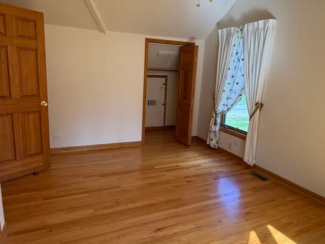 an empty room with wooden floor and entrance