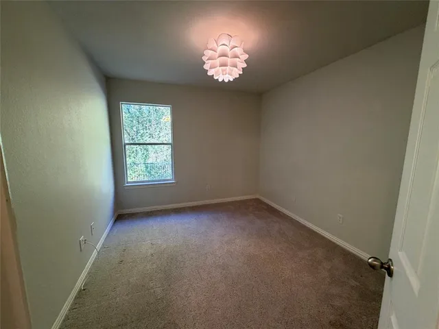 an empty room with a chandelier fan and windows