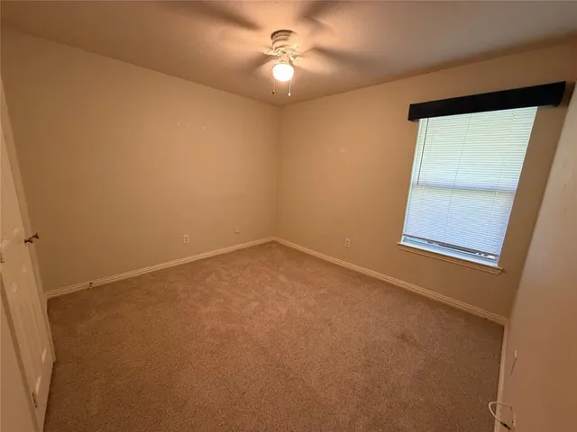 an empty room with a window and a ceiling fan