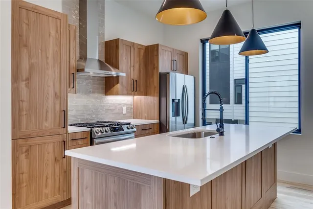 a kitchen with stainless steel appliances granite countertop a sink a refrigerator and a stove