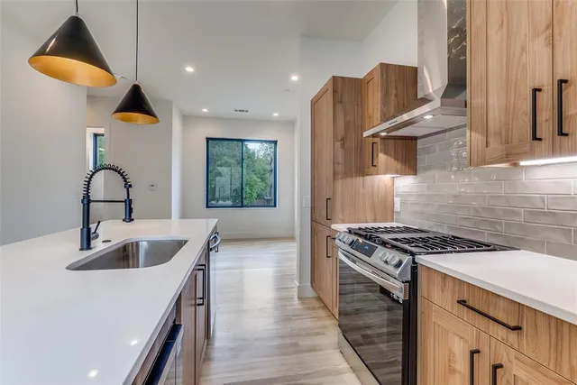 a kitchen with kitchen island stainless steel appliances a sink a stove and a wooden floors