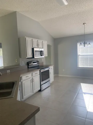 a kitchen with granite countertop a sink cabinets and stainless steel appliances