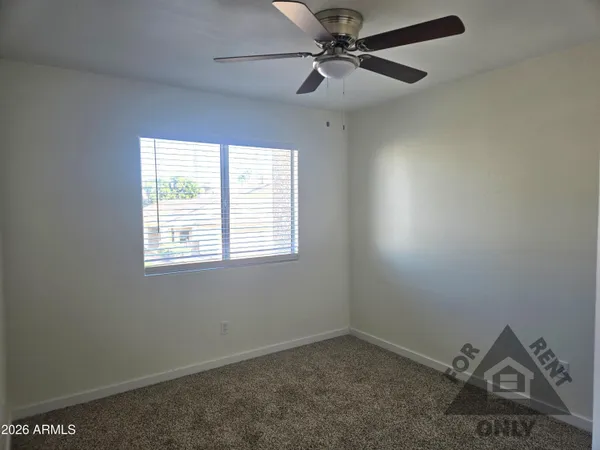 an empty room with a window and a fan