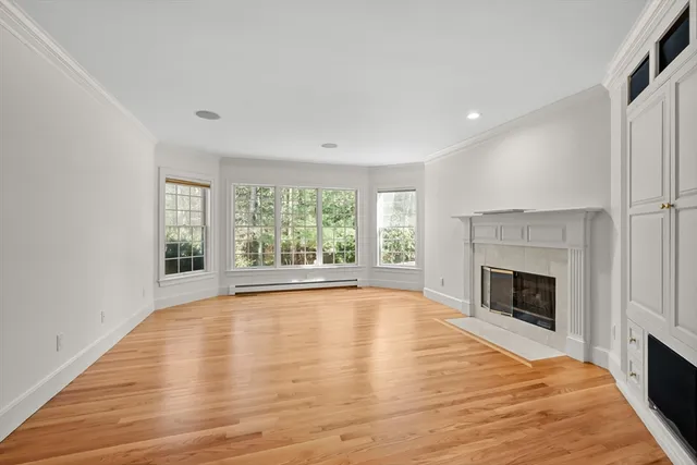 a view of empty room with wooden floor and fireplace