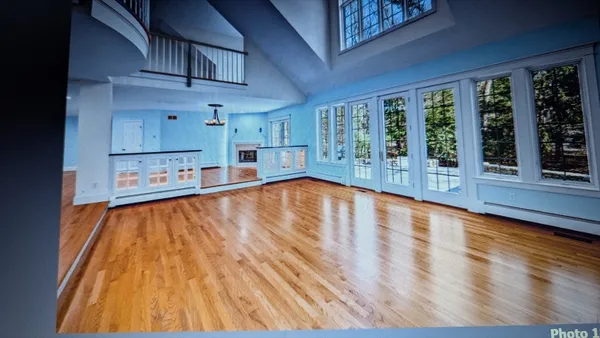 a view of a living room with stainless steel appliances wooden floor and a large window