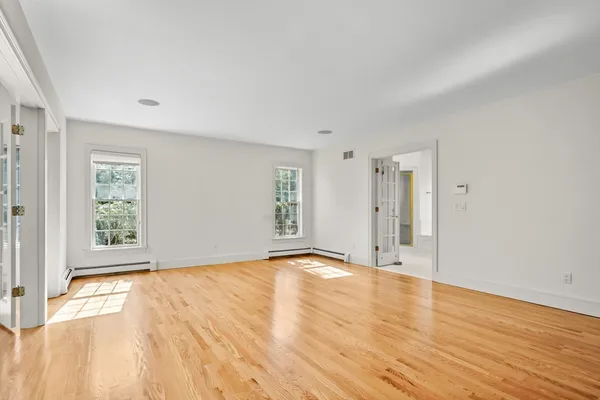a view of an empty room with wooden floor and a window