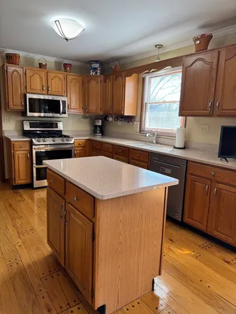 a kitchen with stainless steel appliances a sink a stove a refrigerator cabinets and a window