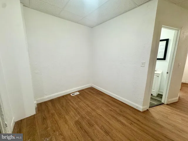 a view of a room with wooden floor and a white wall