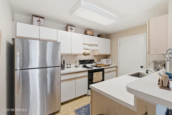 a kitchen with stainless steel appliances a refrigerator sink and white cabinets