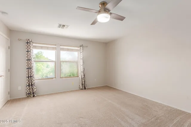 an empty room with windows and fan