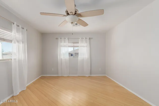 a view of empty room with wooden floor and fan