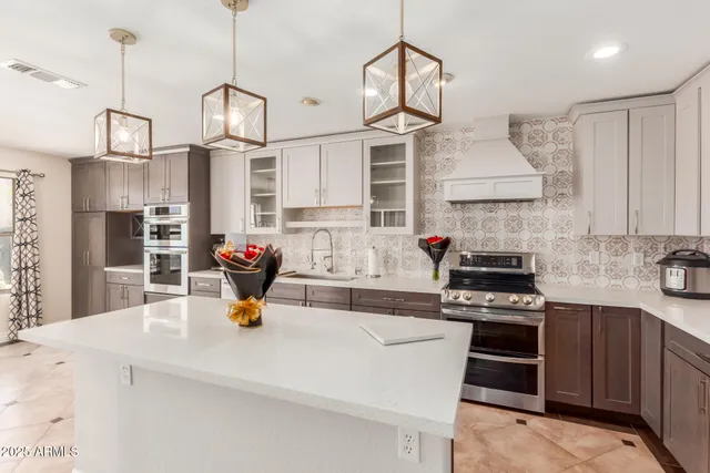 a kitchen with stainless steel appliances granite countertop a sink a stove and a wooden floors