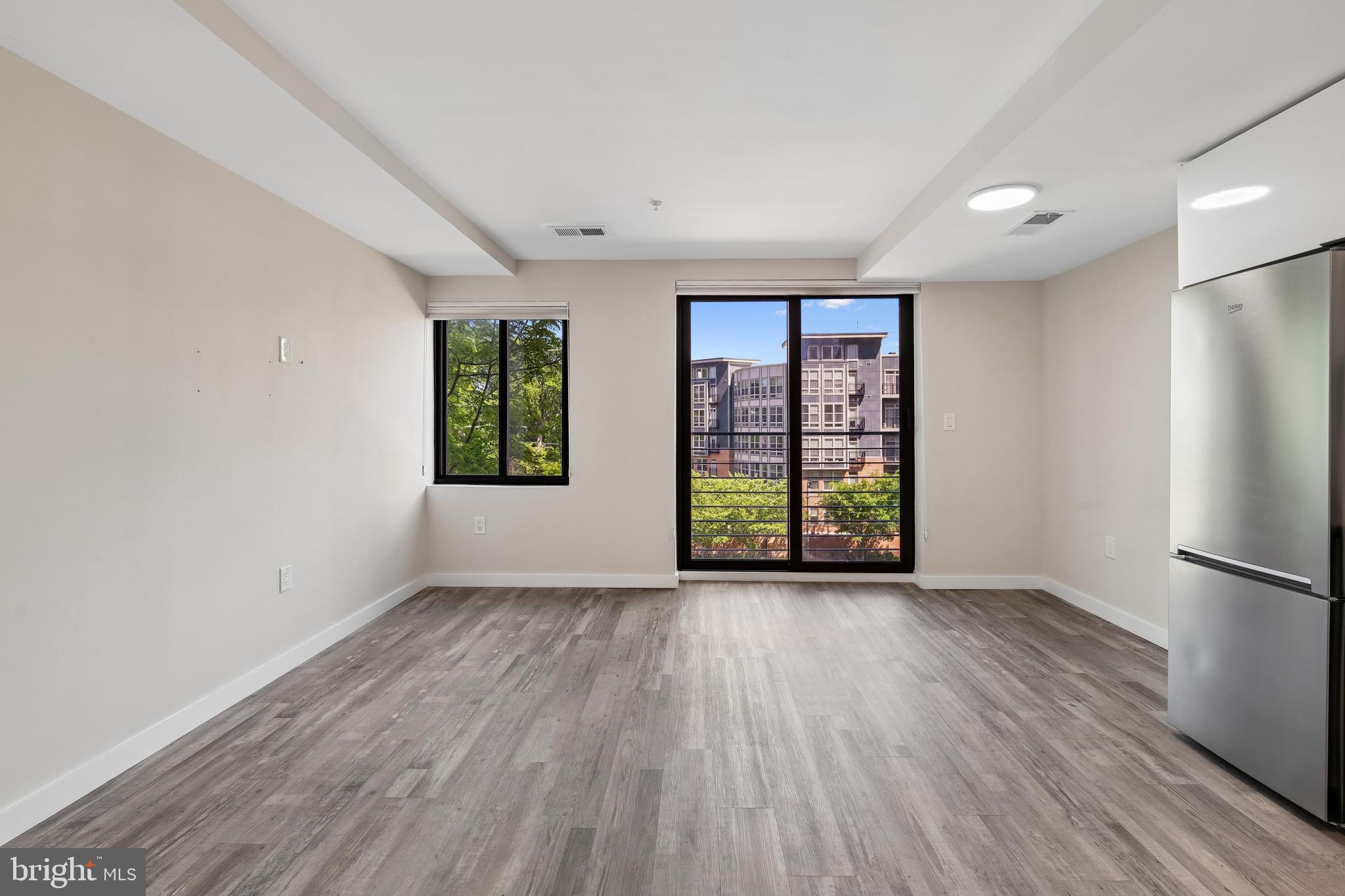 700 Roeder Road, Unit 401 Silver Spring, MD 20910 - Photo 6 of 30 an empty room with wooden floor cabinet and windows