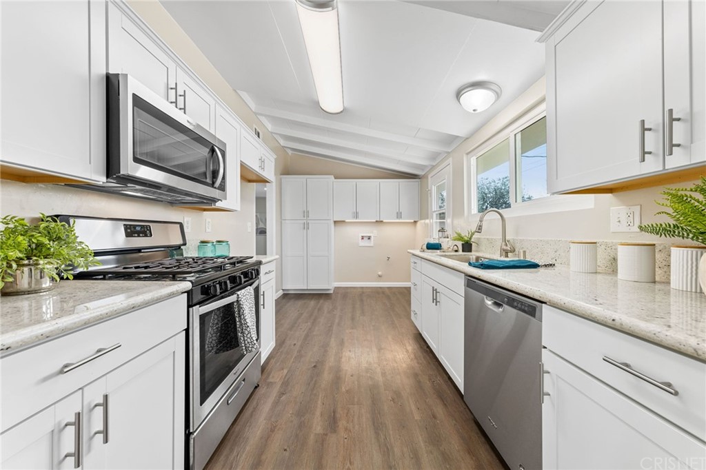 6737 Delco Avenue Winnetka, CA 91306 - Photo 12 of 31 a kitchen with stainless steel appliances granite countertop hardwood floor sink stove and white cabinets