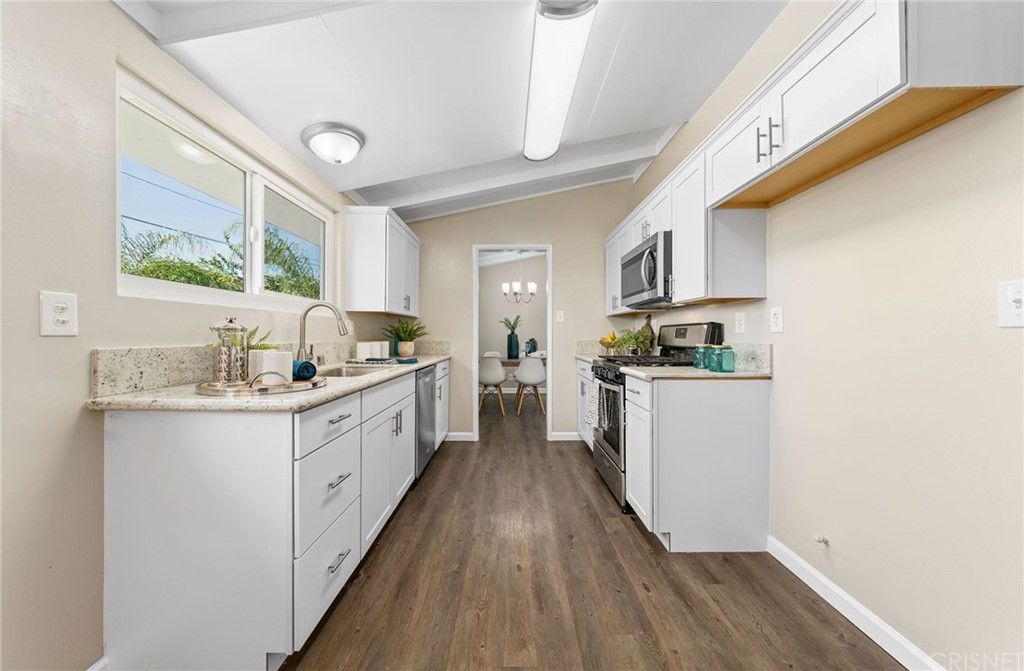 6737 Delco Avenue Winnetka, CA 91306 - Photo 13 of 31 a kitchen with granite countertop a sink cabinets stainless steel appliances and a large window
