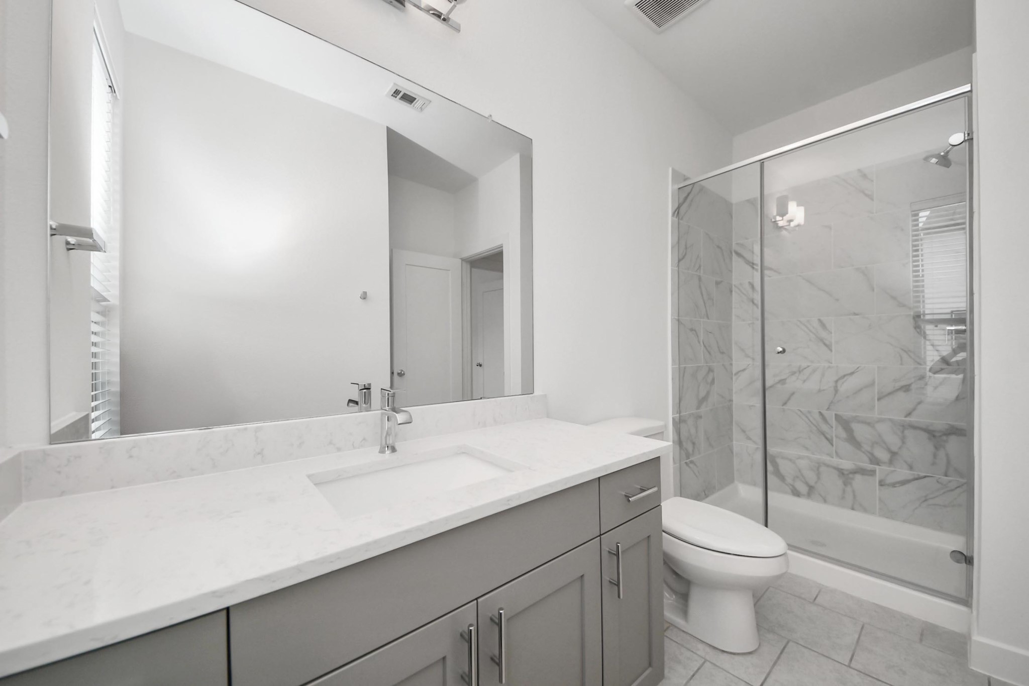 18527 Centro Row Conroe, TX 77385 - Photo 19 of 44 Clean lines define this full bathroom, featuring a glass-enclosed shower and a minimalist vanity set against a serene neutral palette.