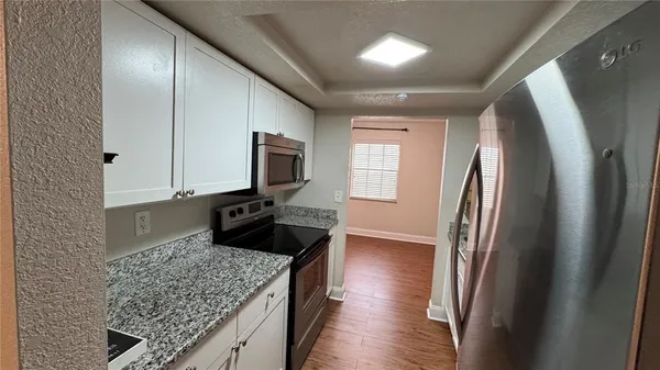 a kitchen with stainless steel appliances granite countertop a refrigerator a stove and a sink with wooden floor