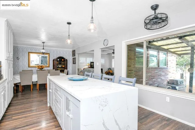 a large kitchen with kitchen island a large counter space a sink appliances and a large window