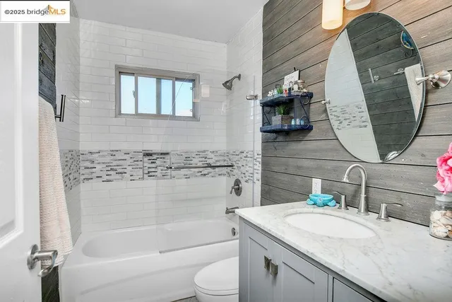 a bathroom with a granite countertop sink vanity mirror bathtub shower and a toilet