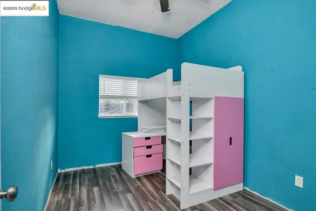a view of an empty room with wooden floor and a ceiling fan