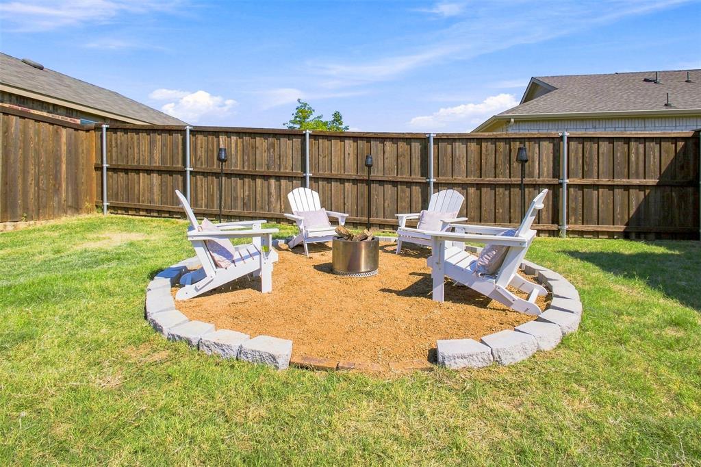 6609 Auburn Dl Road Pilot Point, TX 76258 - Photo 2 of 38 Backyard fire pit area featuring a stone border, loose aggregate ground cover, and a privacy fence