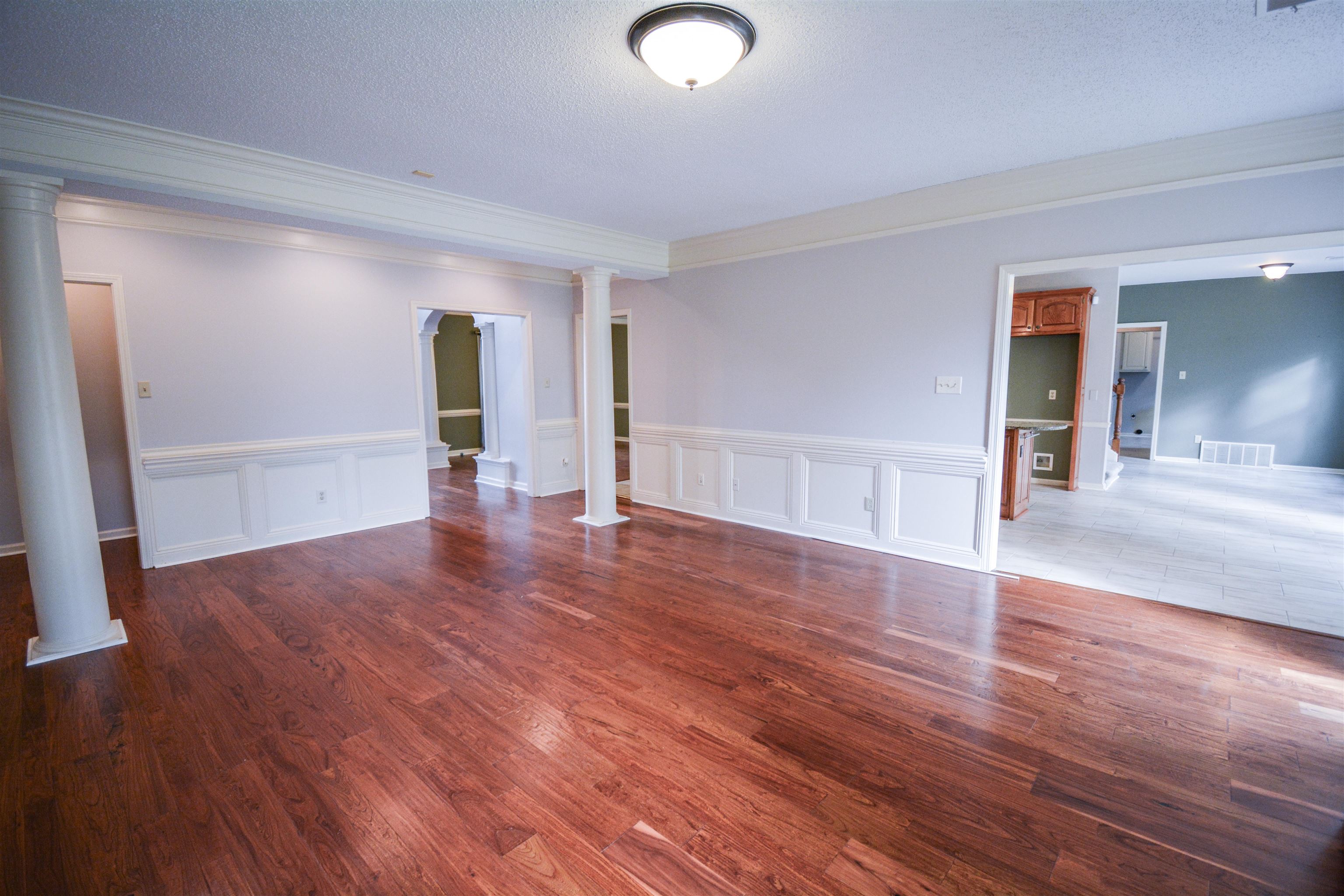 745 Roehampton Court Collierville, TN 38017 - Photo 12 of 40 Spare room featuring crown molding, dark wood finished floors, a textured ceiling, ornate columns, and a decorative wall