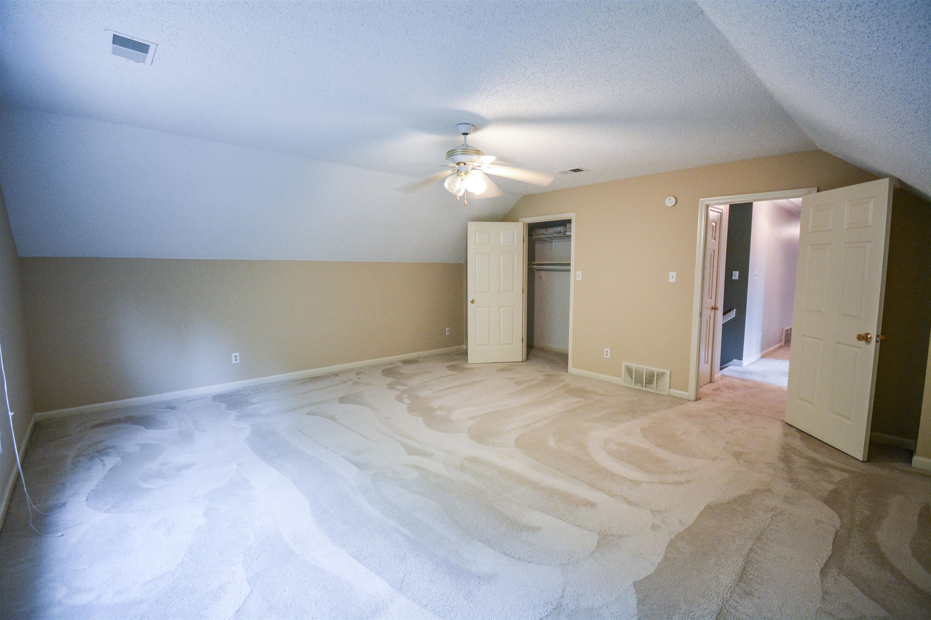 745 Roehampton Court Collierville, TN 38017 - Photo 32 of 40 Unfurnished bedroom featuring lofted ceiling, carpet floors, a textured ceiling, a spacious closet, and a ceiling fan