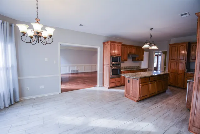 a view of a livingroom with a chandelier fan and windows