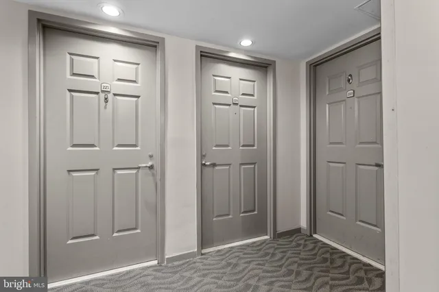 a view of a hallway with wooden floor and a bathroom