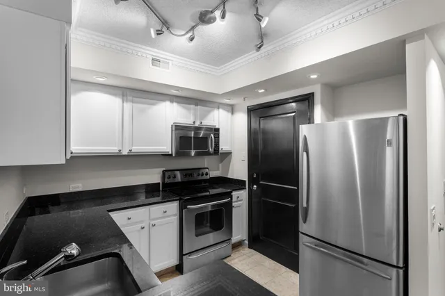 a white kitchen with granite countertop white cabinets and stainless steel appliances
