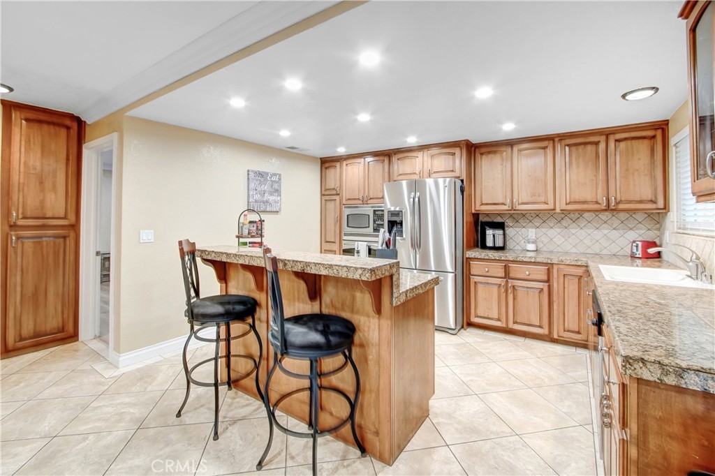 8555 Pigeon Pass Road Moreno Valley, CA 92557 - Photo 11 of 63 a kitchen with stainless steel appliances kitchen island granite countertop a refrigerator and cabinets
