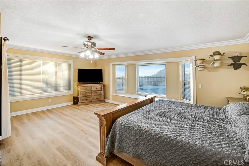 8555 Pigeon Pass Road Moreno Valley, CA 92557 - Photo 13 of 63 a bedroom with a large bed a flat tv screen and large windows