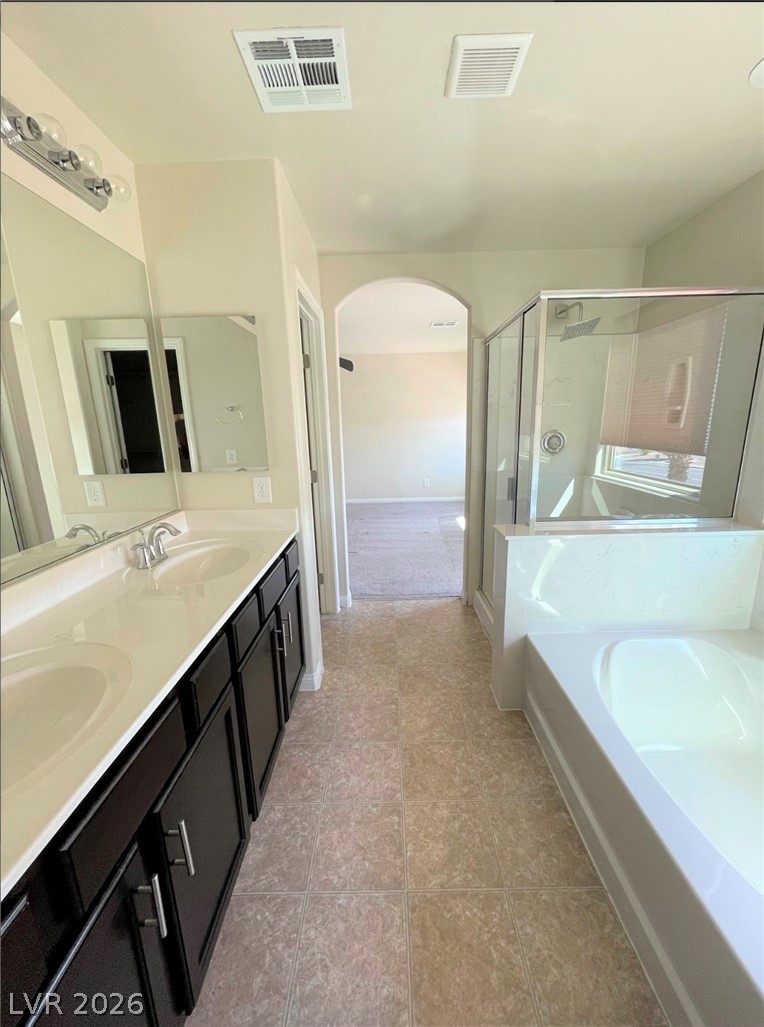 7063 Claythorn Road Las Vegas, NV 89148 - Photo 14 of 30 A well-appointed primary bathroom features a dual vanity, a spacious soaking tub, and a glass-enclosed shower.