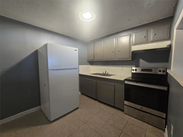 a kitchen with stainless steel appliances granite countertop a refrigerator and a stove top oven